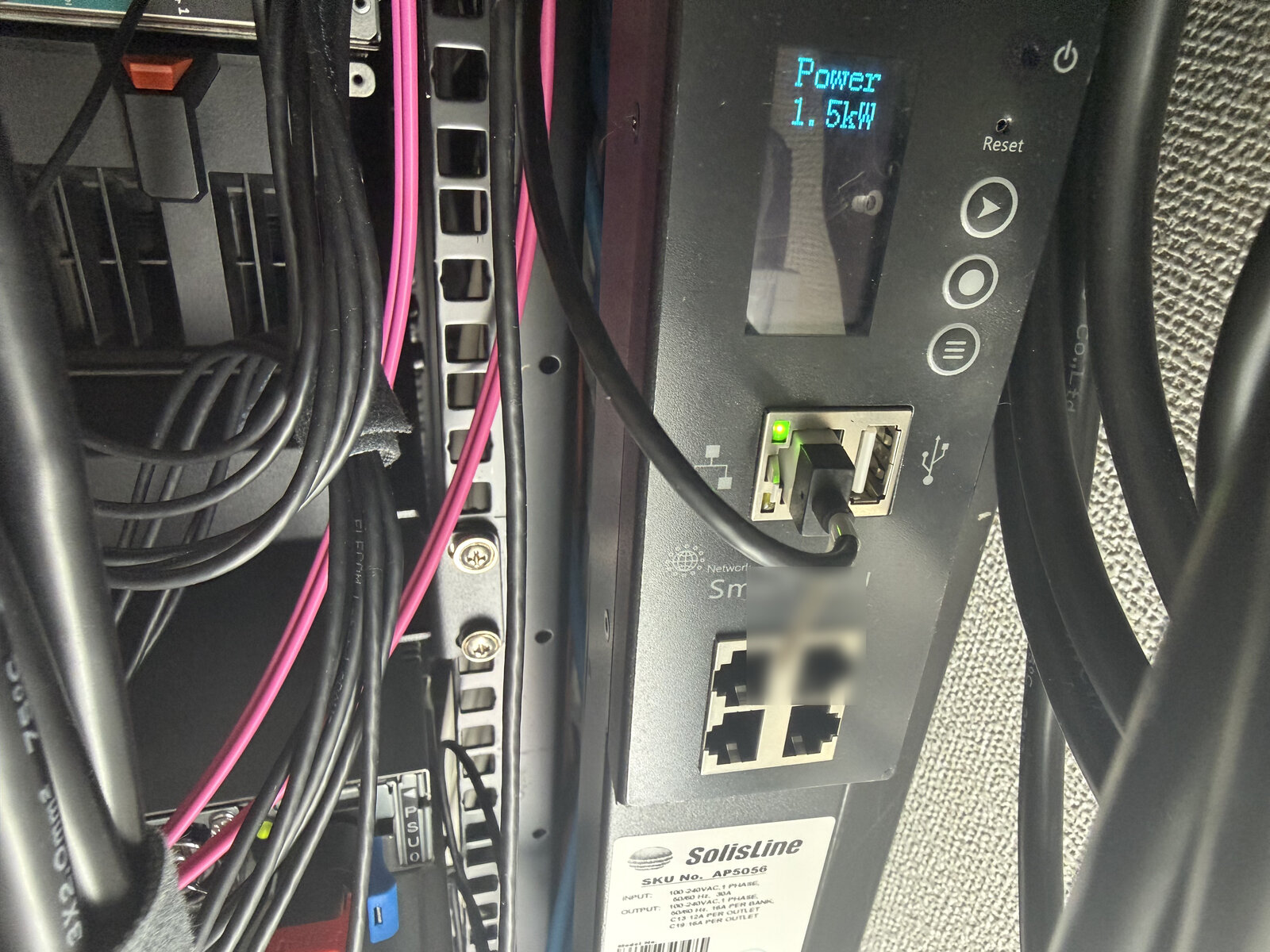 ラックに設置した SolisLine AP5056 の操作パネル。LCD に「Power 1.5kW」と表示され、その下に LAN ポート（リンク点灯中）と USB ポート、さらに RS-485 用の 4 連 RJ-45 ポートが並ぶ。下部の銘板に型番 AP5056 と「1 PHASE, 30A」が読める